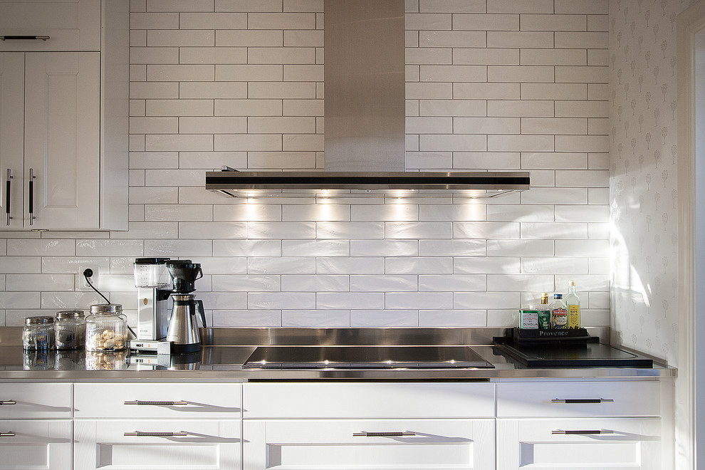 Moderne Küche mit weißen Schränken, Küchenrückwand in Weiß, Rückwand aus Porzellanfliesen und Küchengeräten aus Edelstahl in Denver