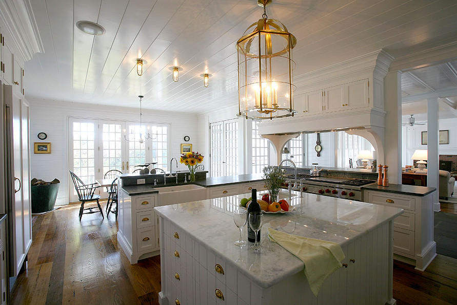 This is an example of a small traditional enclosed kitchen in Boston with white cabinets, stainless steel appliances, terracotta flooring and an island.