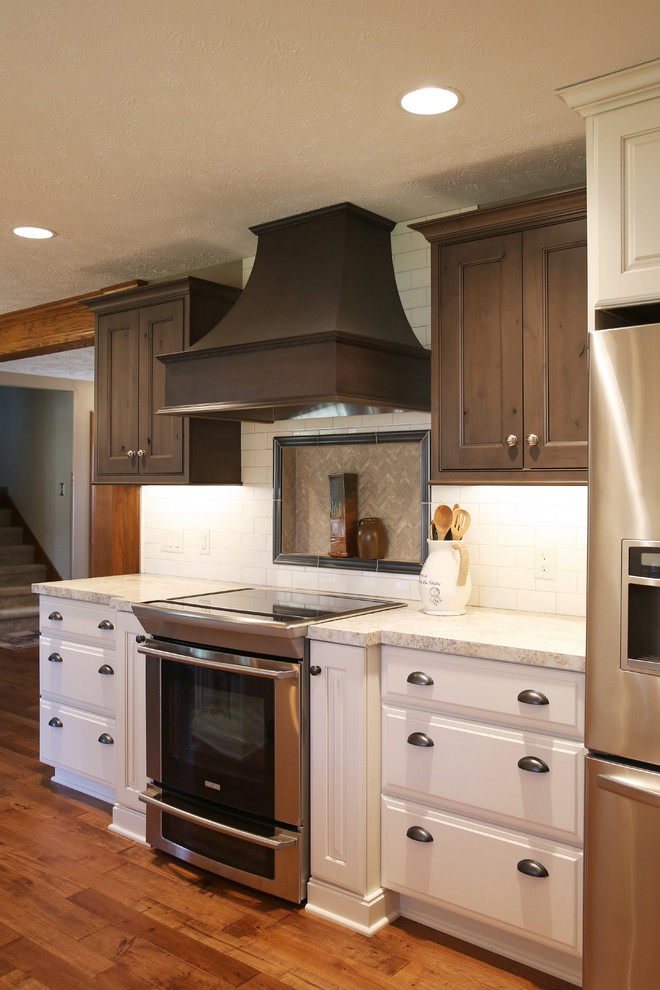 Inspiration for a mid-sized transitional u-shaped medium tone wood floor and brown floor kitchen pantry remodel in Omaha with a double-bowl sink, shaker cabinets, dark wood cabinets, quartz countertops, white backsplash, subway tile backsplash, stainless steel appliances, a peninsula and white countertops