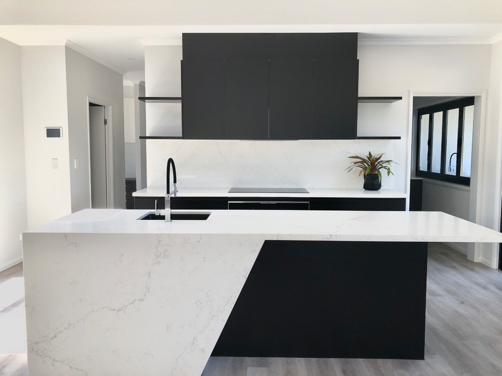 Inspiration for a modern galley open plan kitchen in Sunshine Coast with a submerged sink, black cabinets, engineered stone countertops, white splashback, an island and white worktops.