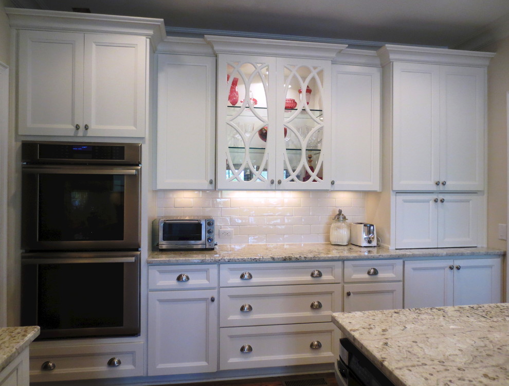 Ejemplo de cocina clásica renovada con armarios con paneles empotrados, puertas de armario blancas, encimera de granito, electrodomésticos de acero inoxidable, salpicadero blanco y salpicadero de azulejos tipo metro