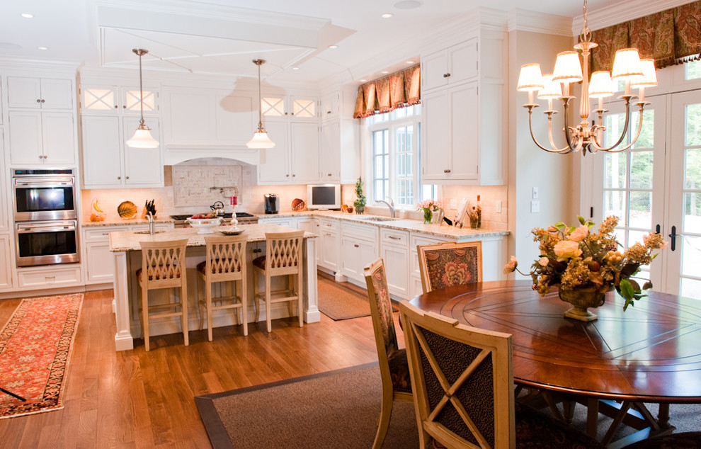 Inspiration for a huge timeless u-shaped medium tone wood floor eat-in kitchen remodel in Bridgeport with recessed-panel cabinets, white cabinets, granite countertops, beige backsplash, ceramic backsplash, an island, an undermount sink and paneled appliances