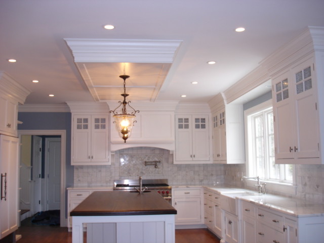 Exempel på ett stort klassiskt kök, med en rustik diskho, luckor med infälld panel, vita skåp, träbänkskiva, stänkskydd i keramik, mellanmörkt trägolv, en köksö, vitt stänkskydd och integrerade vitvaror