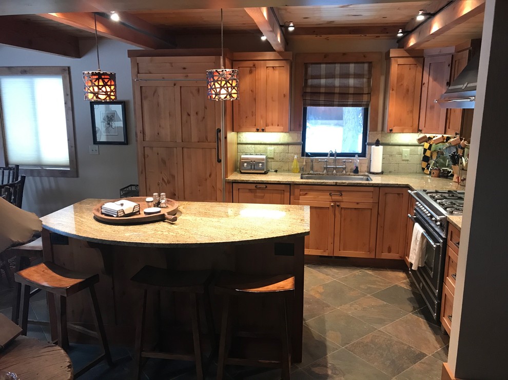 Bild på ett mellanstort amerikanskt l-kök, med en undermonterad diskho, skåp i shakerstil, skåp i ljust trä, granitbänkskiva, stänkskydd i travertin, integrerade vitvaror, skiffergolv och en köksö