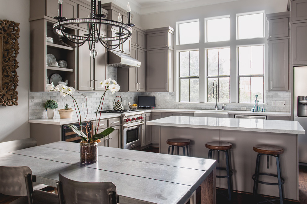 Klassische Wohnküche in L-Form mit Landhausspüle, Schrankfronten mit vertiefter Füllung, grauen Schränken, Küchenrückwand in Weiß, Küchengeräten aus Edelstahl, dunklem Holzboden und Kücheninsel in Dallas