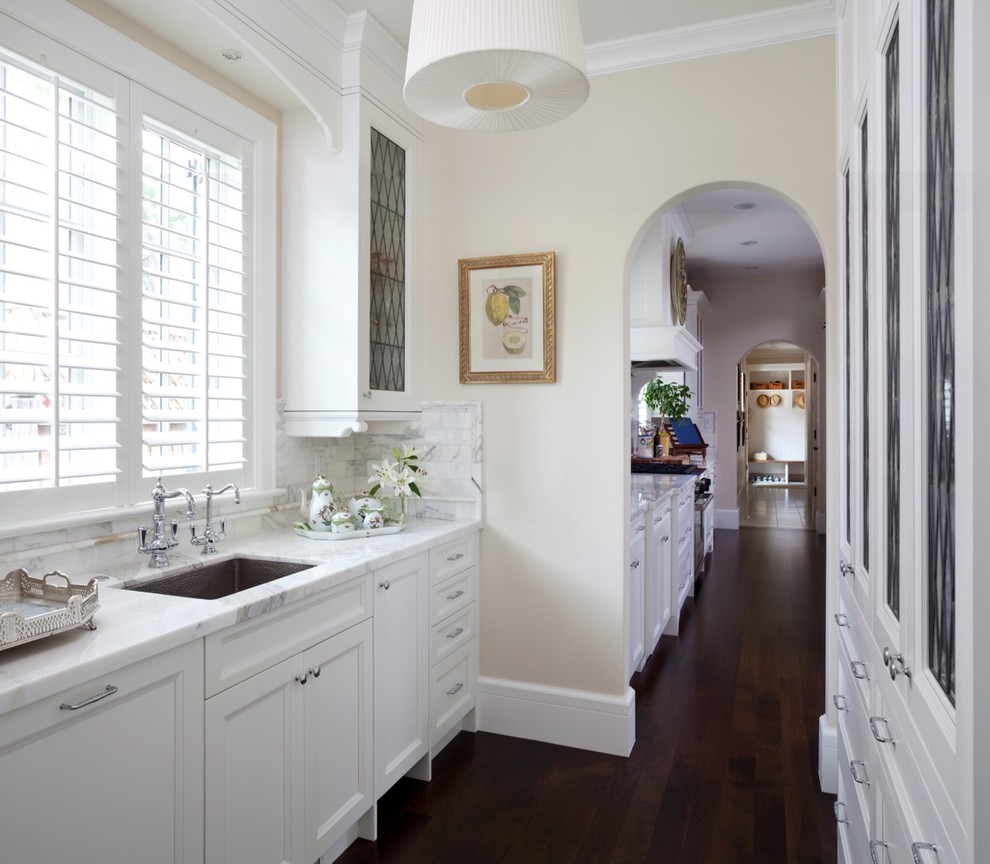 Exempel på ett stort klassiskt kök, med en undermonterad diskho, luckor med infälld panel, vita skåp, marmorbänkskiva, vitt stänkskydd, stänkskydd i tunnelbanekakel, vita vitvaror, mörkt trägolv och en köksö