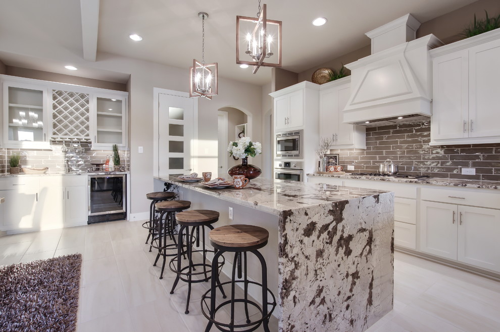 Photo of a traditional l-shaped kitchen in Austin with shaker cabinets, white cabinets, grey splashback, metro tiled splashback, stainless steel appliances, an island and beige floors.