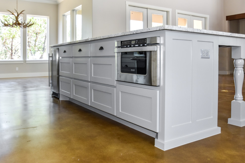 Bild på ett lantligt kök med öppen planlösning, med skåp i shakerstil, grå skåp, granitbänkskiva, rostfria vitvaror, betonggolv och en köksö
