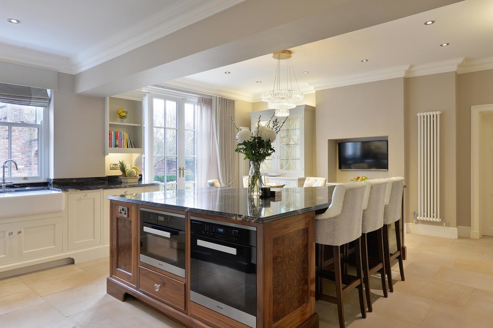 This is an example of a large contemporary kitchen/diner in Other with a belfast sink, recessed-panel cabinets, granite worktops, integrated appliances and an island.