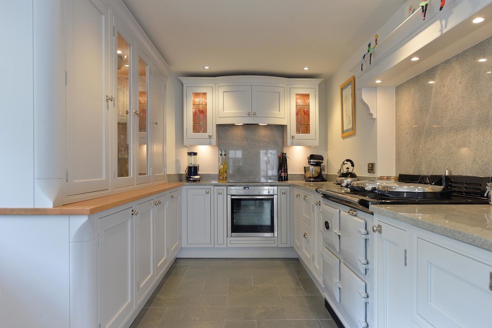 Geschlossene, Mittelgroße Klassische Küche in L-Form mit Schrankfronten mit vertiefter Füllung, weißen Schränken und Küchenrückwand in Grau in Sonstige