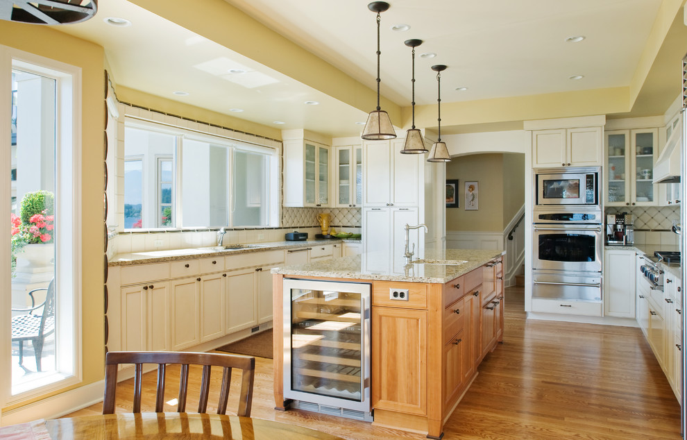 シアトルにあるトラディショナルスタイルのおしゃれなキッチン (アンダーカウンターシンク、白いキャビネット、白いキッチンパネル、シルバーの調理設備) の写真