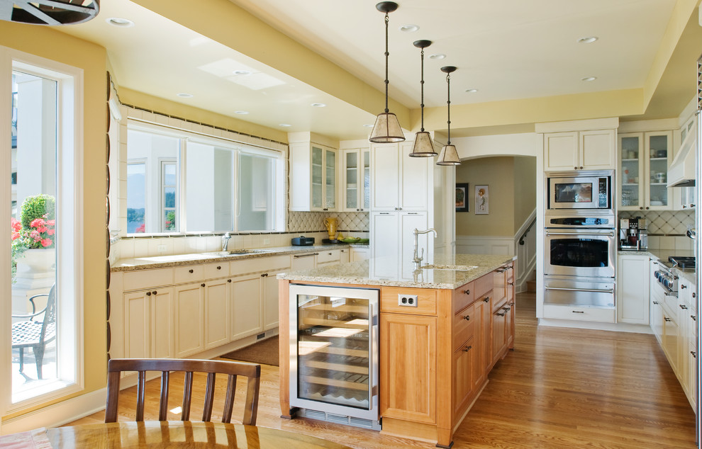 Inspiration for a traditional u-shaped kitchen/diner in Seattle with a submerged sink, white cabinets, white splashback and stainless steel appliances.