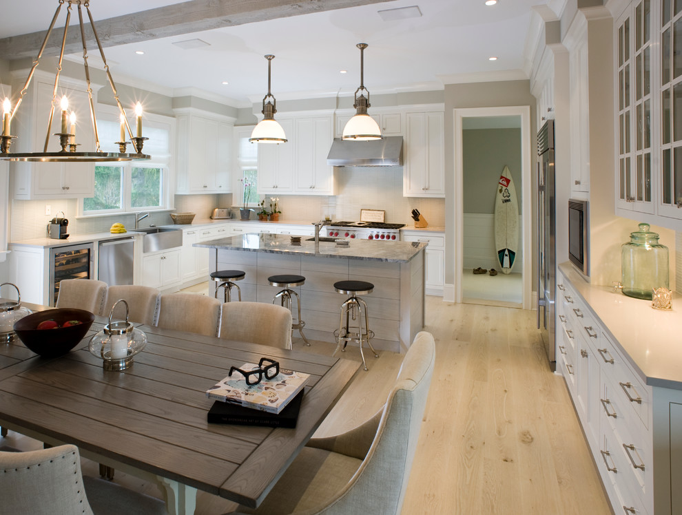 Cette image montre une cuisine chalet avec des portes de placard blanches, une crédence blanche et un électroménager en acier inoxydable.