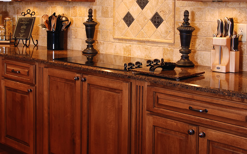 Imagen de cocina tradicional de tamaño medio con armarios con paneles con relieve, puertas de armario de madera en tonos medios, encimera de granito, salpicadero beige y salpicadero de azulejos de piedra