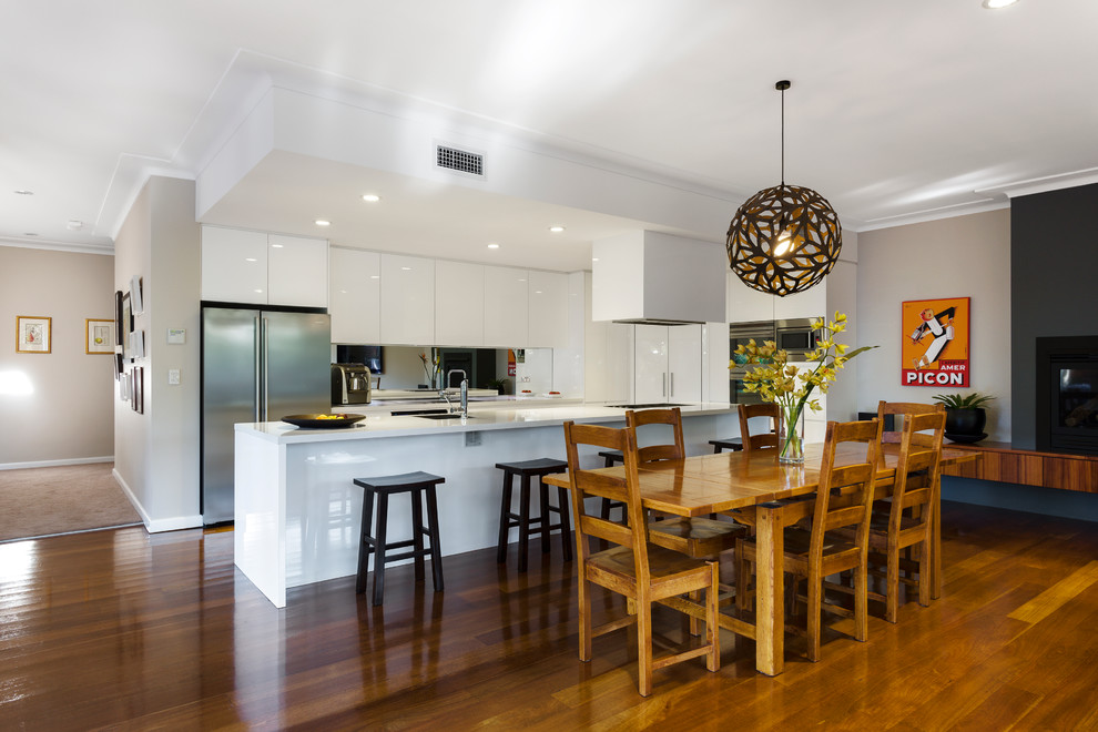 This is an example of a medium sized traditional kitchen in Sydney with an integrated sink, white cabinets, mirror splashback, medium hardwood flooring and an island.