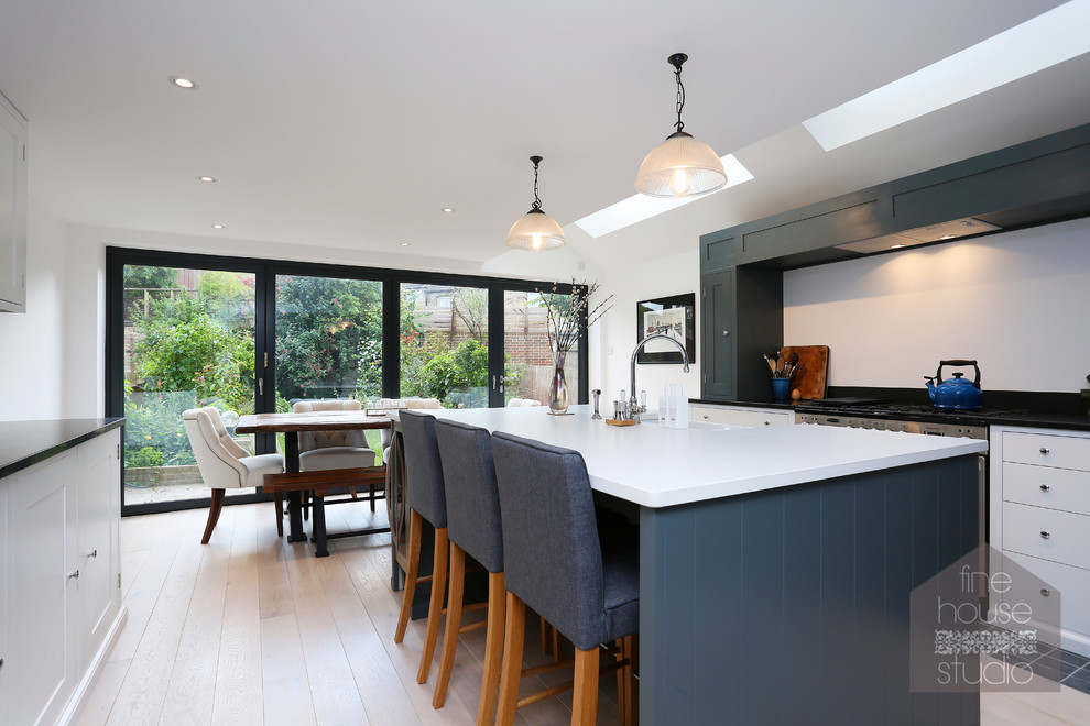 Modern inredning av ett stort kök och matrum, med en undermonterad diskho, grå skåp, ljust trägolv och en köksö