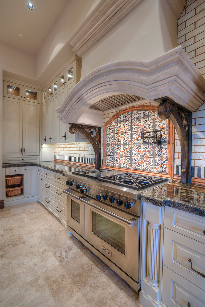 Medelhavsstil inredning av ett mycket stort kök, med en rustik diskho, luckor med infälld panel, rostfria vitvaror, skåp i mellenmörkt trä, granitbänkskiva, beige stänkskydd, stänkskydd i mosaik, travertin golv och en köksö