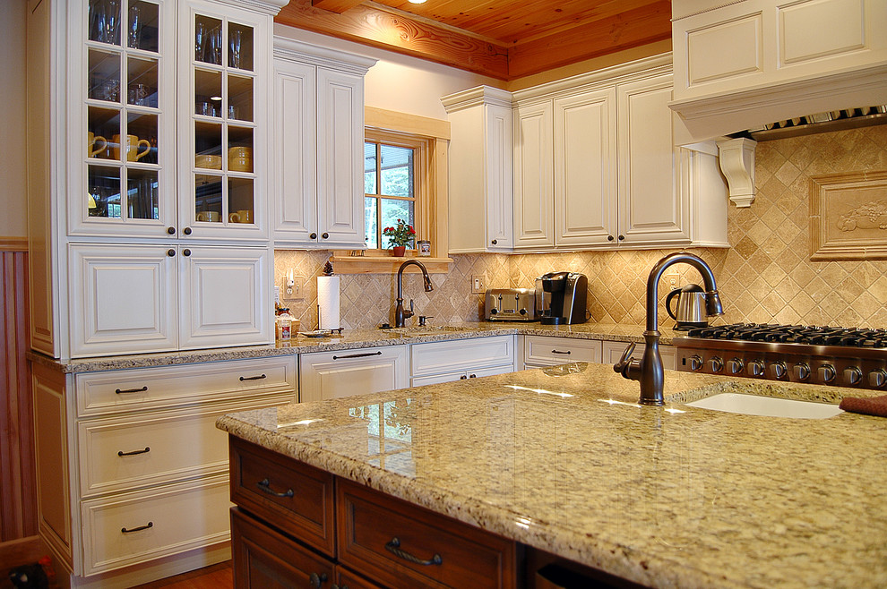 Enclosed kitchen - mid-sized traditional l-shaped medium tone wood floor enclosed kitchen idea in Boston with an undermount sink, shaker cabinets, white cabinets, granite countertops, ceramic backsplash, stainless steel appliances, an island and beige backsplash