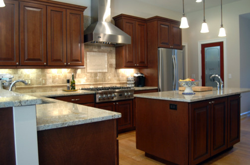 Photo of a large traditional l-shaped enclosed kitchen in Boston with a belfast sink, recessed-panel cabinets, dark wood cabinets, granite worktops, ceramic splashback, stainless steel appliances, medium hardwood flooring and an island.