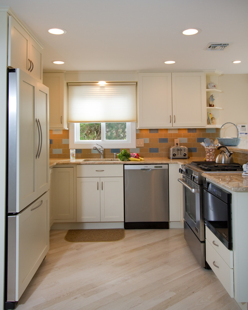 Foto på ett litet maritimt u-kök, med en undermonterad diskho, luckor med infälld panel, vita skåp, granitbänkskiva, flerfärgad stänkskydd, stänkskydd i glaskakel, rostfria vitvaror, ljust trägolv och en halv köksö