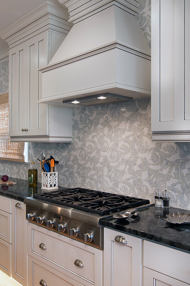Foto på ett stort lantligt kök, med luckor med infälld panel, vita skåp, grått stänkskydd, rostfria vitvaror och en köksö