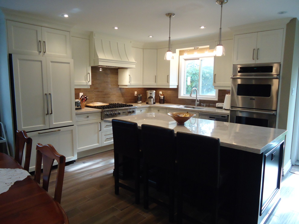 Medium sized contemporary l-shaped kitchen in Toronto with a built-in sink, shaker cabinets, white cabinets, brown splashback, matchstick tiled splashback, integrated appliances, medium hardwood flooring and an island.