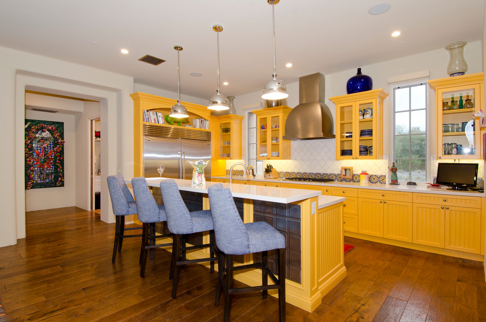 Mediterrane Küche in L-Form mit gelben Schränken, Küchenrückwand in Weiß, dunklem Holzboden und Kücheninsel in Phoenix