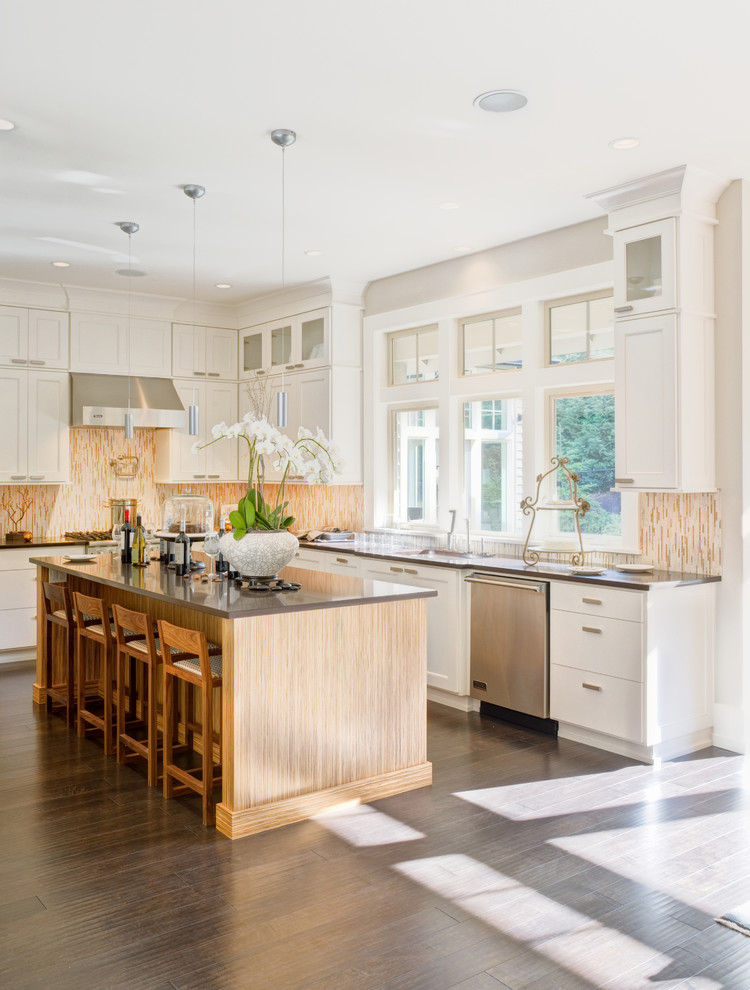 Mid-sized elegant l-shaped dark wood floor and brown floor eat-in kitchen photo in Los Angeles with shaker cabinets, white cabinets, beige backsplash, matchstick tile backsplash, stainless steel appliances, an island, a single-bowl sink, solid surface countertops and gray countertops