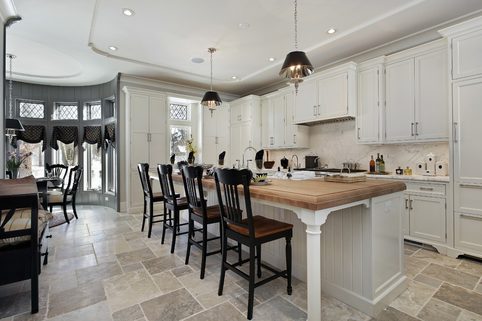 Eat-in kitchen - large traditional l-shaped ceramic tile eat-in kitchen idea in Los Angeles with a double-bowl sink, shaker cabinets, white cabinets, wood countertops, stainless steel appliances, two islands, white backsplash and porcelain backsplash
