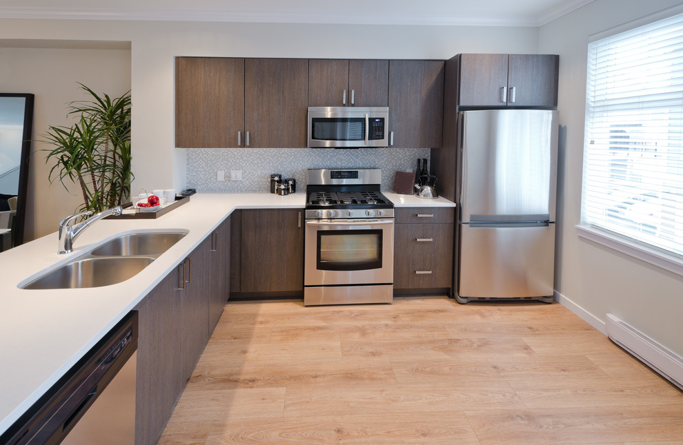 Photo of a medium sized contemporary l-shaped enclosed kitchen in Los Angeles with a double-bowl sink, flat-panel cabinets, medium wood cabinets, limestone worktops, stainless steel appliances, light hardwood flooring, no island and grey splashback.
