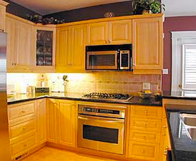 Esempio di una cucina ad U con lavello a doppia vasca, ante con bugna sagomata, ante in legno chiaro, paraspruzzi beige, elettrodomestici in acciaio inossidabile e parquet chiaro