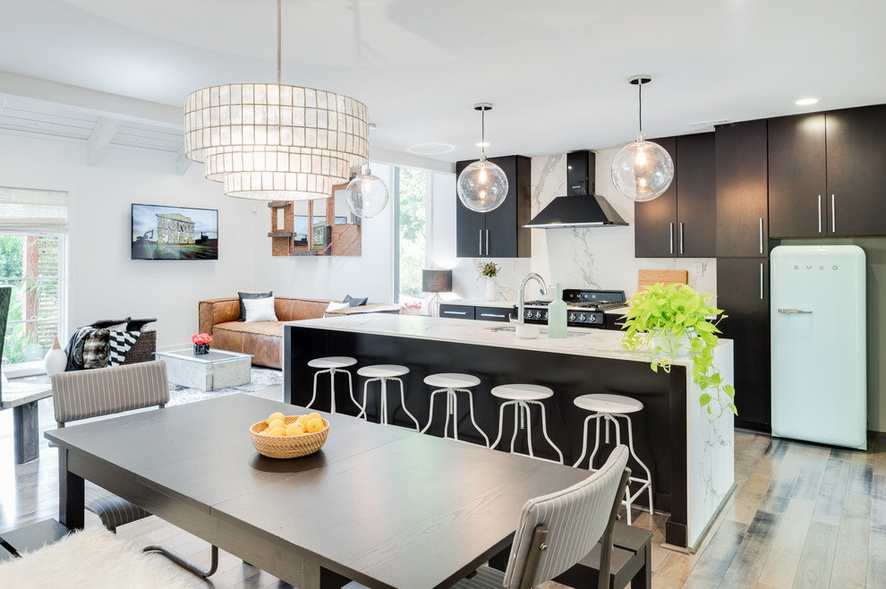 This is an example of a large contemporary galley open plan kitchen in Atlanta with a submerged sink, an island, flat-panel cabinets, black cabinets, marble worktops, grey splashback, stone slab splashback, stainless steel appliances and light hardwood flooring.