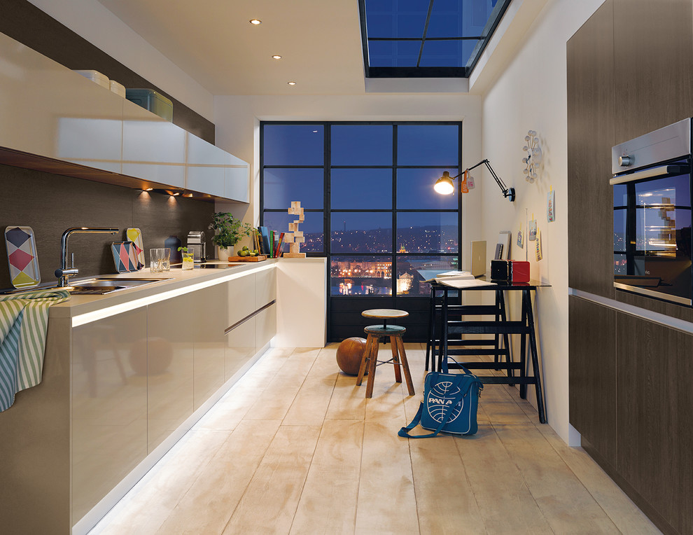 Foto di una cucina parallela minimal chiusa e di medie dimensioni con ante lisce, ante beige e parquet chiaro