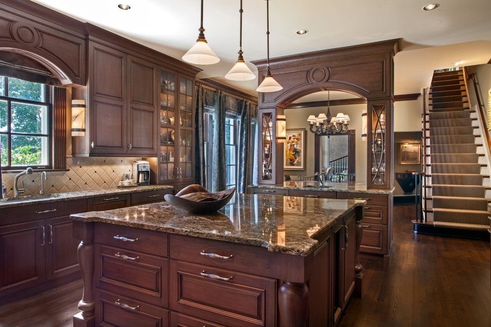 Inspiration for a large timeless dark wood floor and brown floor kitchen remodel in Nashville with an undermount sink, raised-panel cabinets, dark wood cabinets, granite countertops, paneled appliances, two islands, multicolored backsplash and multicolored countertops
