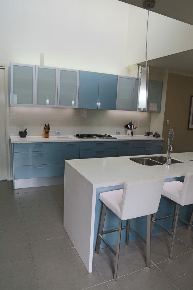 Moderne Küche mit flächenbündigen Schrankfronten, blauen Schränken, Küchengeräten aus Edelstahl und Porzellan-Bodenfliesen in Central Coast