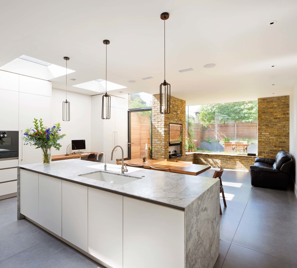 Medium sized scandi single-wall open plan kitchen in London with white cabinets, marble worktops, an island and grey floors.
