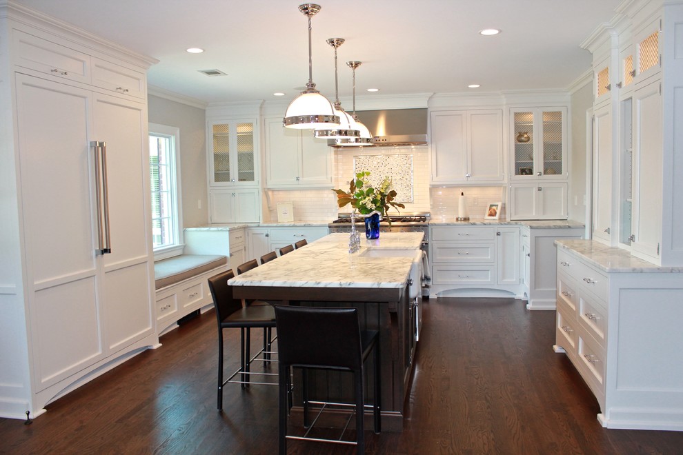 Eat-in kitchen - large transitional u-shaped dark wood floor eat-in kitchen idea in New York with a farmhouse sink, recessed-panel cabinets, white cabinets, marble countertops, white backsplash, subway tile backsplash, paneled appliances and an island