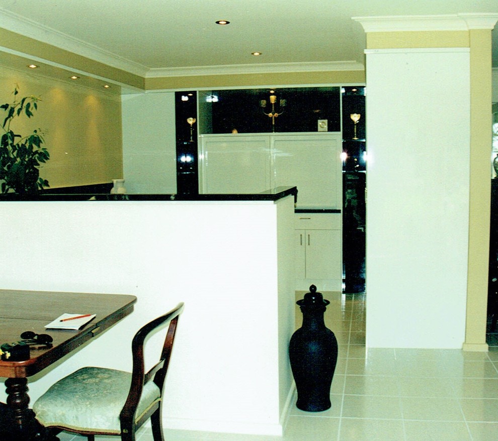 Bild på ett mellanstort funkis kök, med släta luckor, vita skåp, laminatbänkskiva, svart stänkskydd, svarta vitvaror och klinkergolv i keramik