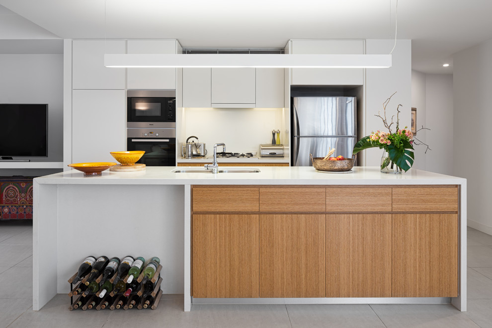 Esempio di una cucina contemporanea con lavello sottopiano, ante lisce, ante bianche, paraspruzzi bianco, elettrodomestici in acciaio inossidabile e pavimento grigio