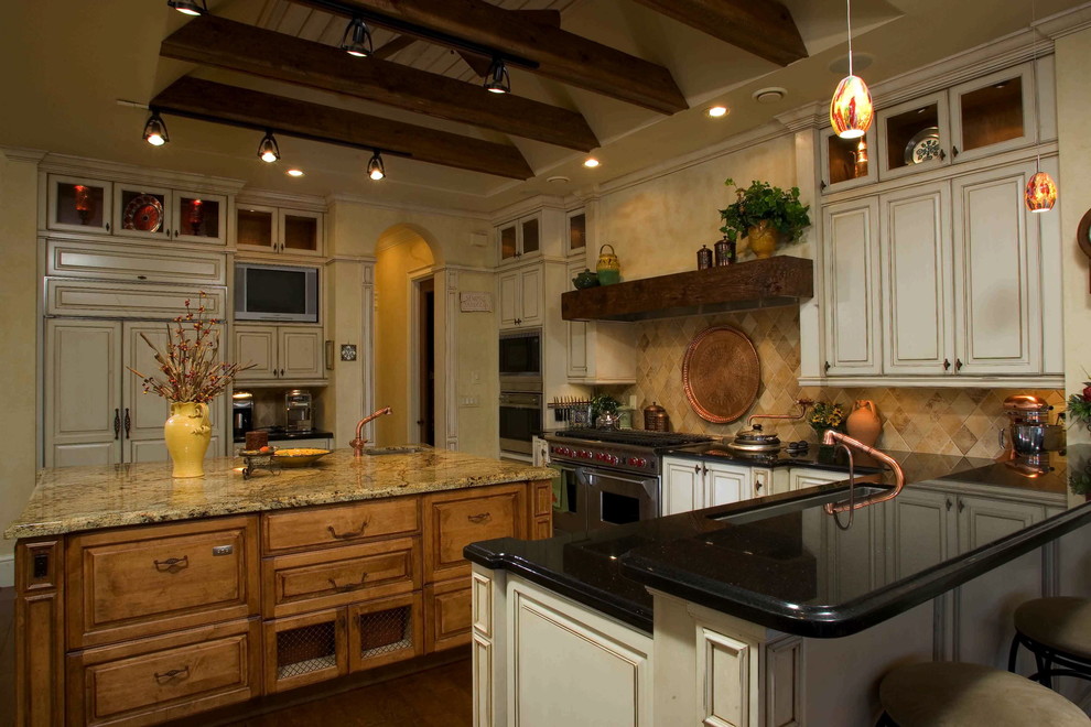 Cette photo montre une grande cuisine américaine méditerranéenne en U avec un plan de travail en granite, une crédence beige, un électroménager en acier inoxydable, un sol en bois brun et îlot.