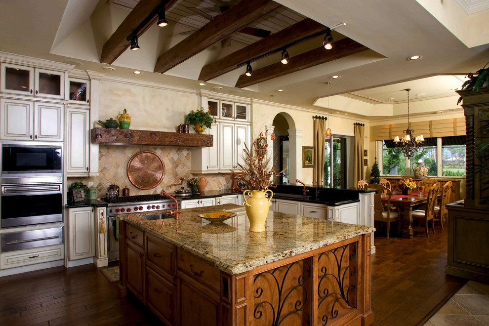 Foto de cocina mediterránea grande con encimera de granito, salpicadero beige, electrodomésticos de acero inoxidable, una isla y suelo de madera en tonos medios