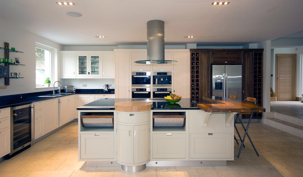 Photo of a contemporary kitchen in Manchester with recessed-panel cabinets, stainless steel appliances and wood worktops.