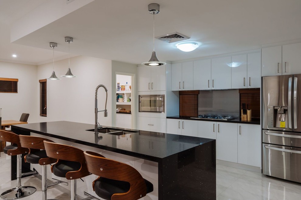 Moderne Küche mit Unterbauwaschbecken, schwarzen Schränken, Mineralwerkstoff-Arbeitsplatte, Küchenrückwand in Weiß, Rückwand aus Stein, Küchengeräten aus Edelstahl, hellem Holzboden und Kücheninsel in Perth