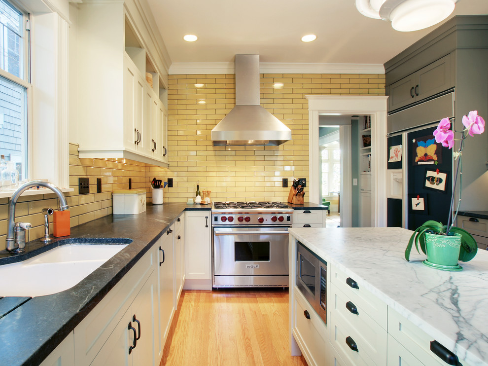 Foto de cocina tradicional con salpicadero amarillo, salpicadero de azulejos tipo metro y electrodomésticos de acero inoxidable