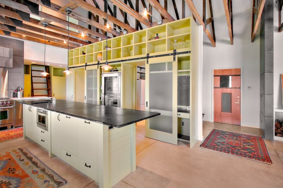 На фото: кухня в стиле лофт с техникой из нержавеющей стали, плоскими фасадами и желтыми фасадами