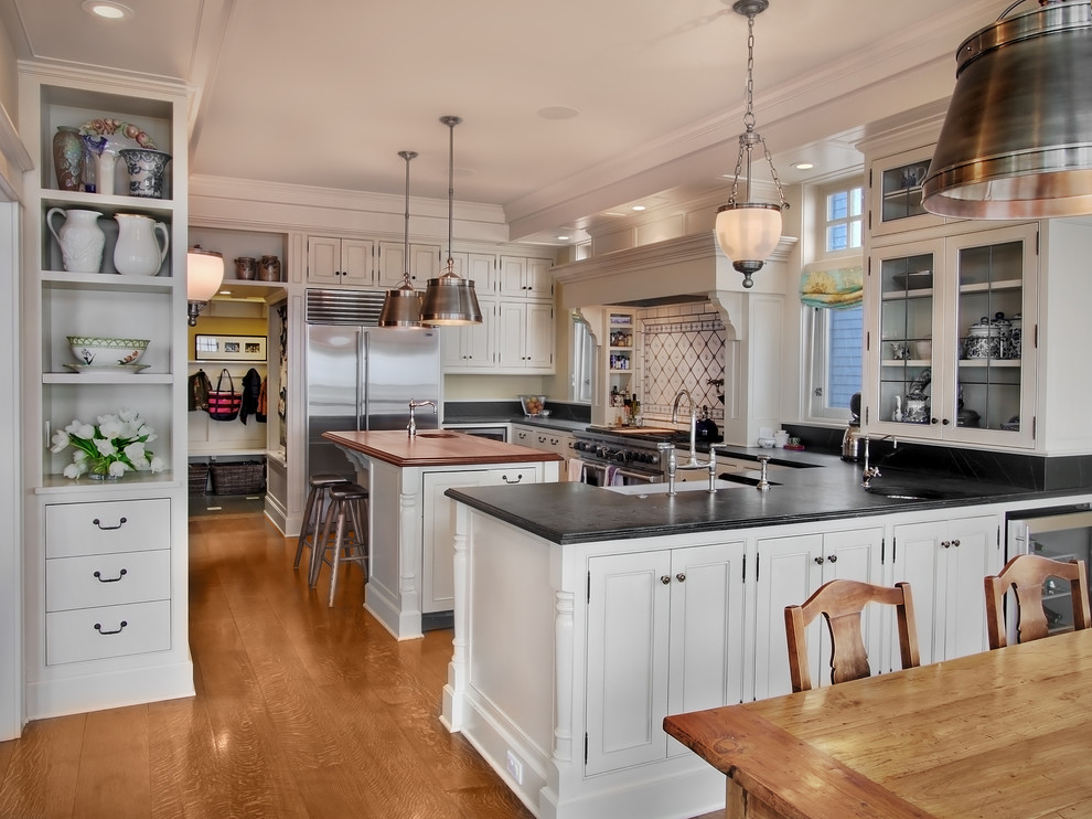 Imagen de cocina clásica con electrodomésticos de acero inoxidable, armarios con rebordes decorativos y puertas de armario blancas