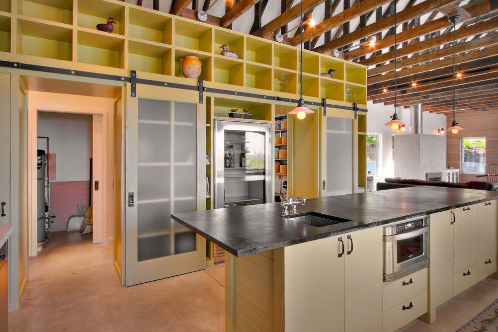 Foto på ett industriellt kök med öppen planlösning, med släta luckor, beige skåp och rostfria vitvaror