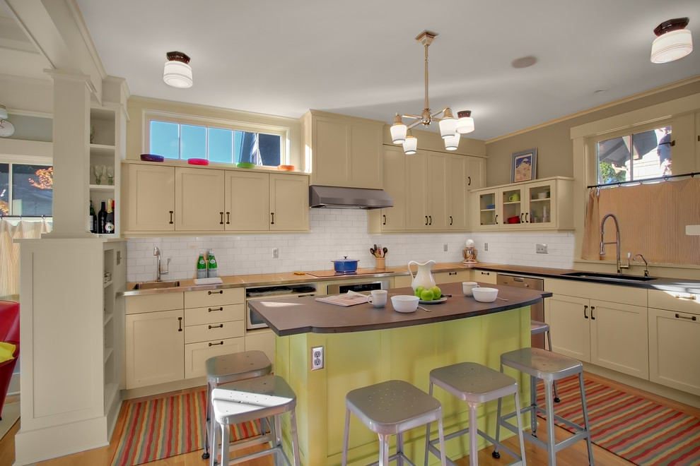 Klassische Küche mit Unterbauwaschbecken, beigen Schränken, Küchenrückwand in Weiß, Rückwand aus Metrofliesen und Küchengeräten aus Edelstahl in Seattle