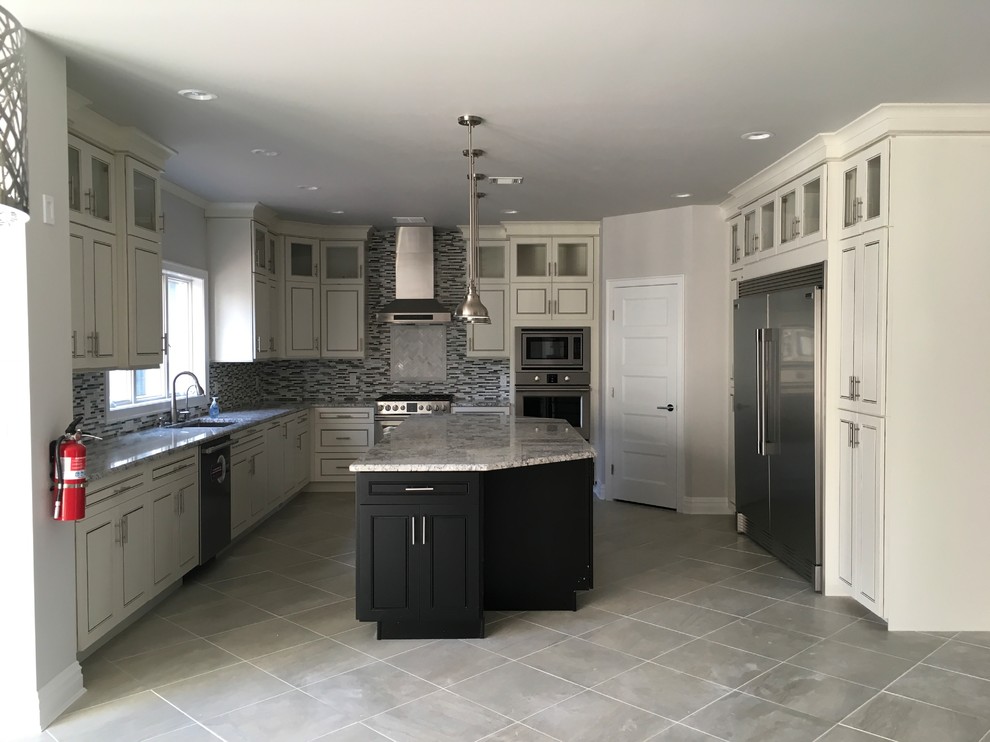 Photo of a medium sized traditional u-shaped open plan kitchen in New York with a submerged sink, recessed-panel cabinets, white cabinets, granite worktops, grey splashback, matchstick tiled splashback, stainless steel appliances, porcelain flooring, an island, grey floors and grey worktops.