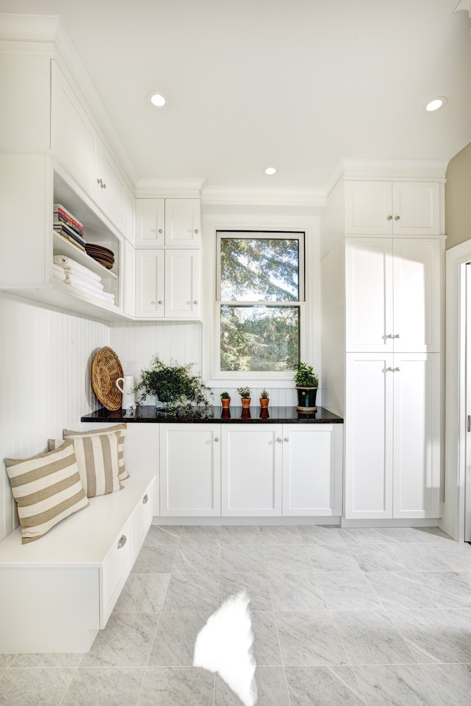 Immagine di una cucina parallela design con lavello da incasso, ante con riquadro incassato, ante bianche, top in superficie solida e pavimento con piastrelle in ceramica